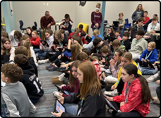 Large group of students seated on the floor.